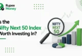 Illustration explaining whether the Nifty Next 50 Index is worth investing in, featuring the RupeeMoney logo, a magnifying glass highlighting the Nifty Next 50, upward-trending charts, and financial growth icons representing long-term investment opportunities in the Indian stock market.
